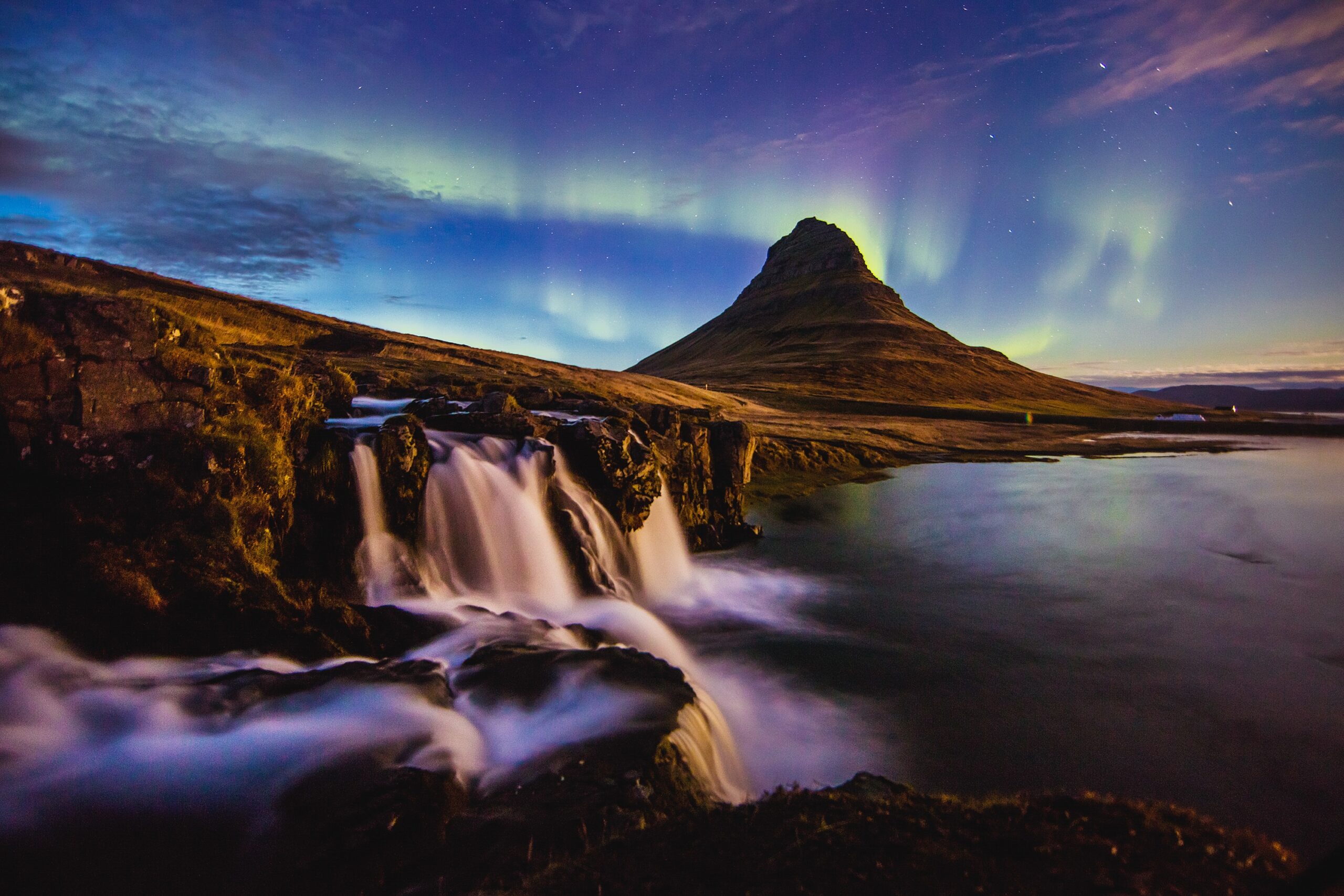 The Northern Lights can be seen above Kirkjufell peak in Iceland with a waterfall in the foreground