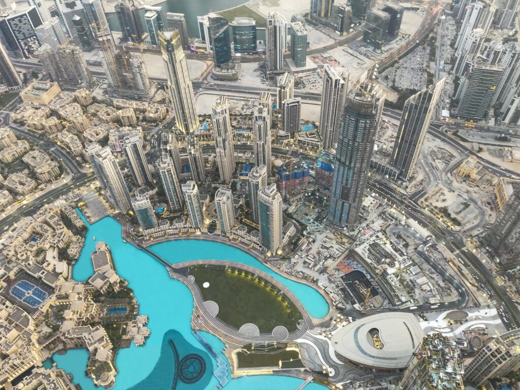 The view from the Burj Khalifa in Dubai. Many skyscrapers can be seen, looking small, and at the base is a large lake of blue water