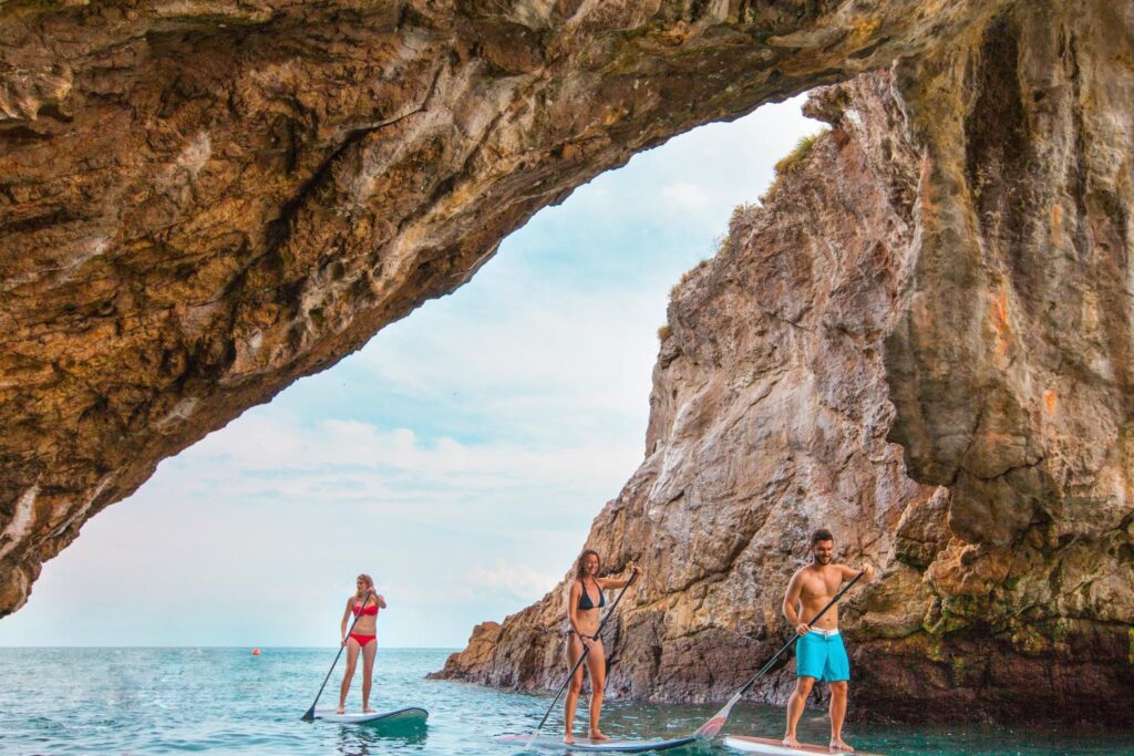 Paddle boarders move through a large cave