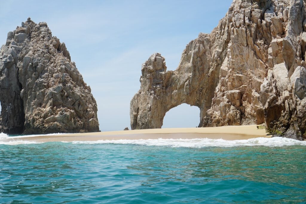 The Arch of Cabo San Lucas, or El Arco, near Los Cabos and Lover's Beach. The rock formation stands over a beach with the blue sea lapping gently against it