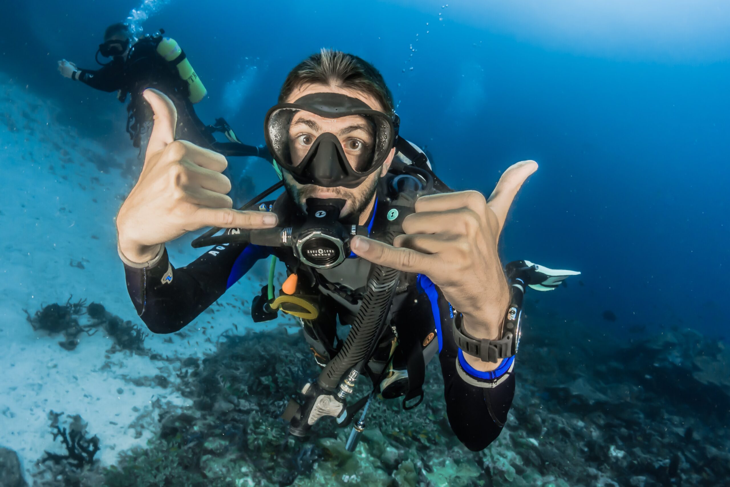 A man makes a sign with his hands while diving
