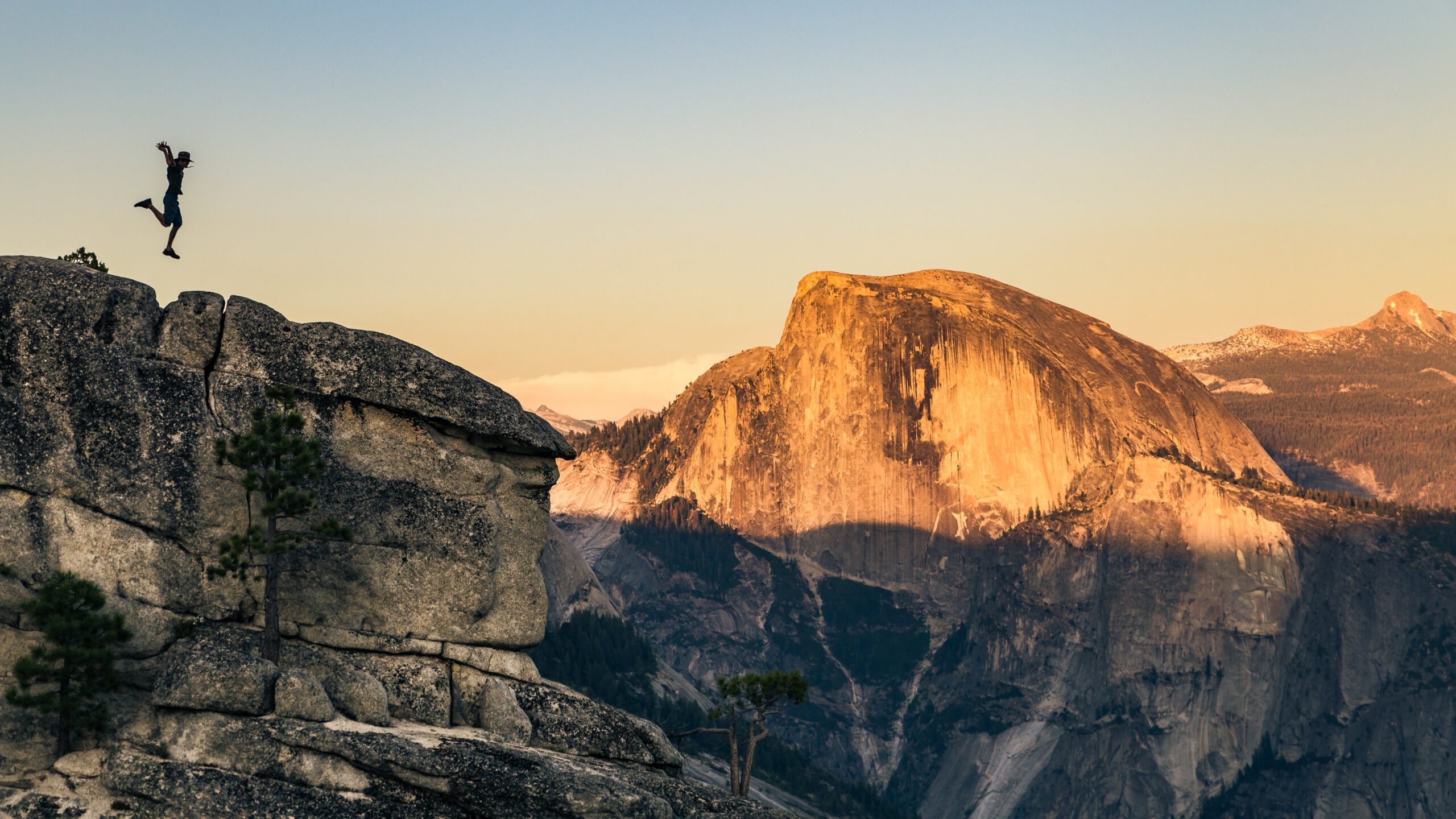 A person jumps on a cliff face in Yosemite at sunset