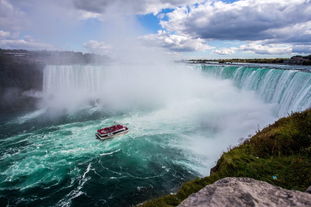 A tourist boat cruises towards the Horseshoe at Niagara Falls. The thundering water is spraying mist everywhere