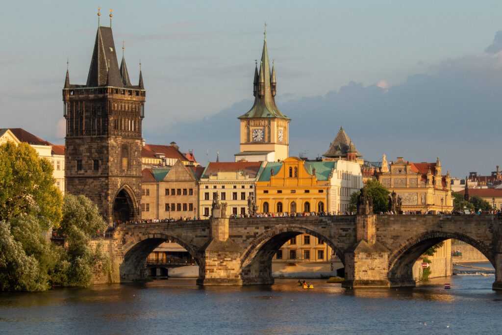 The Charles Bridge meets the bank of the Old Town in Prague. Behind it are medieval buildings and a church tower