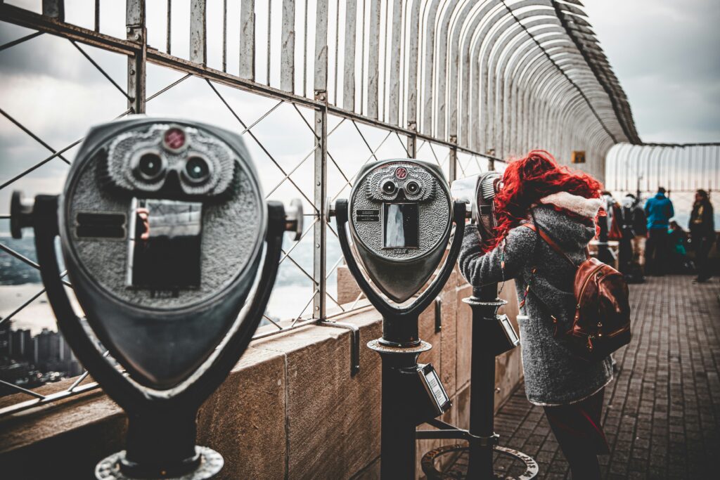 A woman with red hair looks through the famous binoculars on the observation deck of the Empire State Building