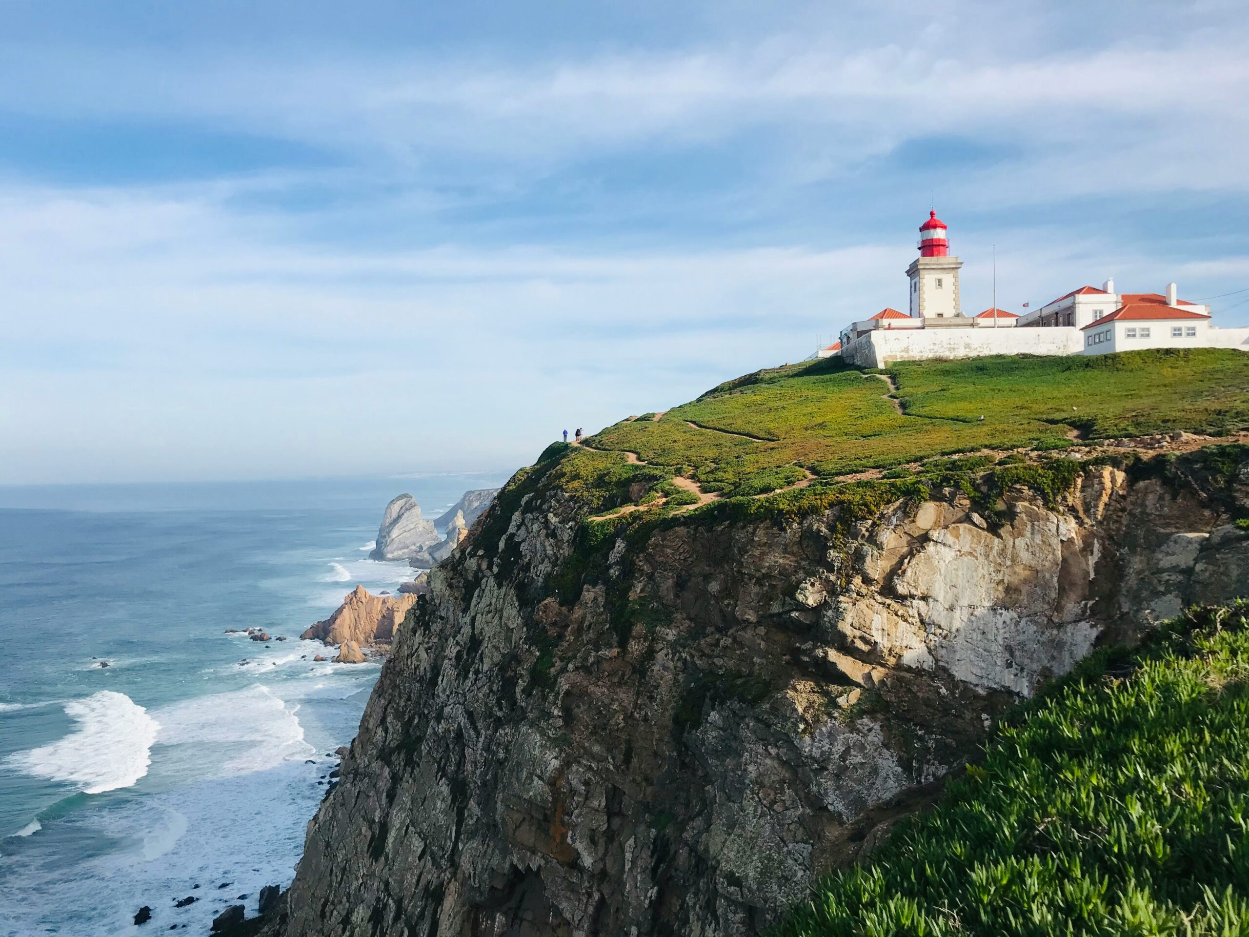 A red and white lighthouse stands on the cliffs overlooking the sea at Cabo da Roca near Sintra and Lisbon